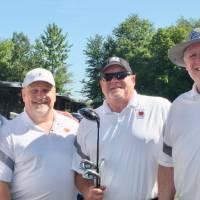 4 men in matching white polos at golf event